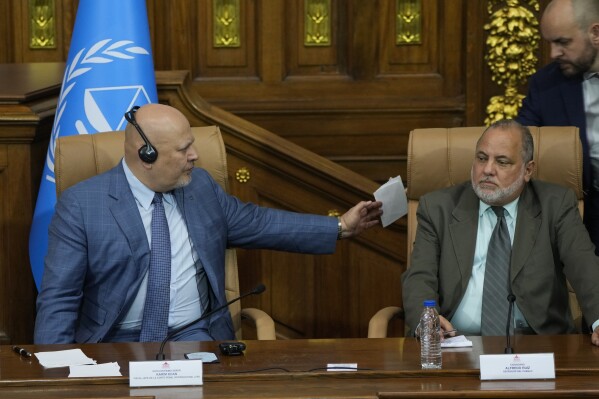 Karim Khan, chief prosecutor of the International Criminal Court, left, passes a piece of paper during a meeting at the National Assembly in Caracas, Venezuela, Monday, April 22, 2024. (AP Photo/Ariana Cubillos)
