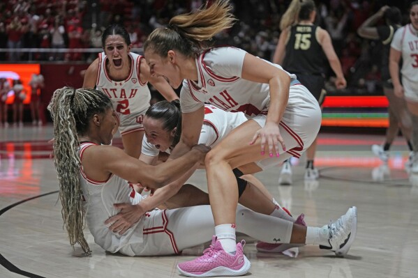 Utah forward Dasia Young, left, sits on the court after making the winning basket while teammates Kennady McQueen, center, Matyson Wilke, right, and Ines Vieira, back left, celebrate after an NCAA college basketball game against Colorado, Friday, Feb. 16, 2024, in Salt Lake City. (AP Photo/Rick Bowmer)
