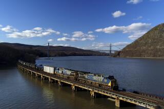 FILE - A CSX Transportation locomotive pulls a train of tank cars across a bridge on the Hudson River along the edge of Bear Mountain State Park near Fort Montgomery, N.Y., on April 26, 2018. Railroads are warning investors that freight shipments will continue to fall this year as the Trump administration's trade fights hamper exports and cheap natural gas causes coal deliveries to dwindle. CSX and Union Pacific both reported a slowdown in freight hauling during the second quarter of 2021. (AP Photo/Julie Jacobson, File)