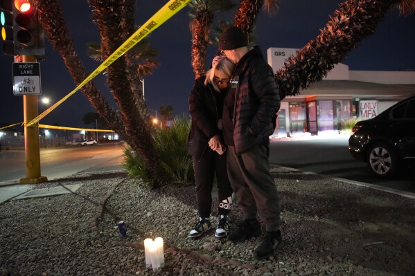 Sean Hathcock, right, kisses Michelle Ashley after the two left candles for victims of a shooting at the University of Nevada, Las Vegas, Wednesday, Dec. 6, 2023, in Las Vegas. The two graduated from the school and live nearby. (AP Photo/John Locher)