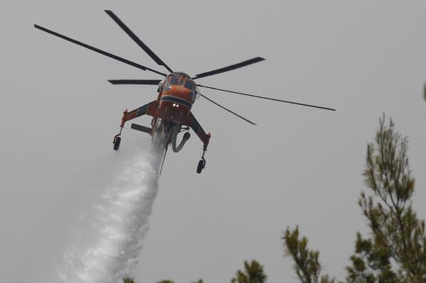 An helicopter drops water over a fire in Galatsonas village on Evia island, about 184 kilometers (115 miles) north of Athens, Greece, Wednesday, Aug. 11, 2021. Hundreds of firefighters from across Europe and the Middle East worked alongside Greek colleagues in rugged terrain Wednesday to contain flareups of the huge wildfires that ravaged Greece's forests for a week, destroying homes and forcing evacuations. (AP Photo/Lefteris Pitarakis)