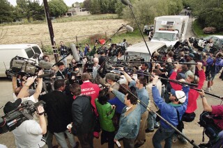 Cameras and microphones surround the San Diego medical examiner outside the compound where 39 members of the Heaven's Gate cult were found dead, apparently by suicide, March 27, 1997.  (AP Photo/Nick Ut)