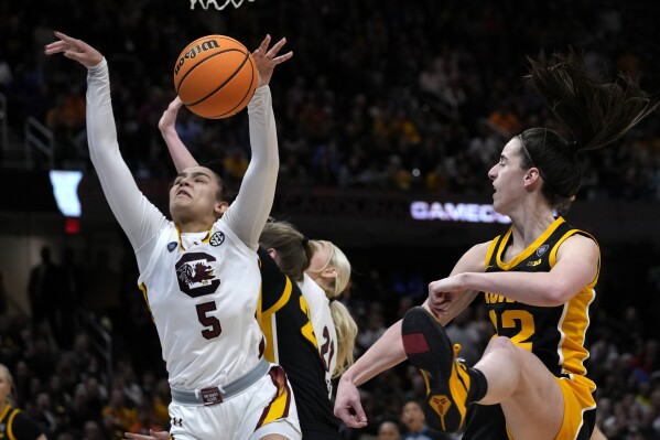 South Carolina guard Tessa Johnson (5) grabs a rebound in front of Iowa guard Caitlin Clark (22) during the second half of the Final Four college basketball championship game in the women's NCAA Tournament, Sunday, April 7, 2024, in Cleveland. (AP Photo/Carolyn Kaster)