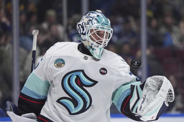 Seattle Kraken goalie Joey Daccord tosses the puck in the air after the whistle during the third period of an NHL hockey game against the Vancouver Canucks, in Vancouver, on Wednesday, April 2, 2025. (Darryl Dyck/The Canadian Press via AP)