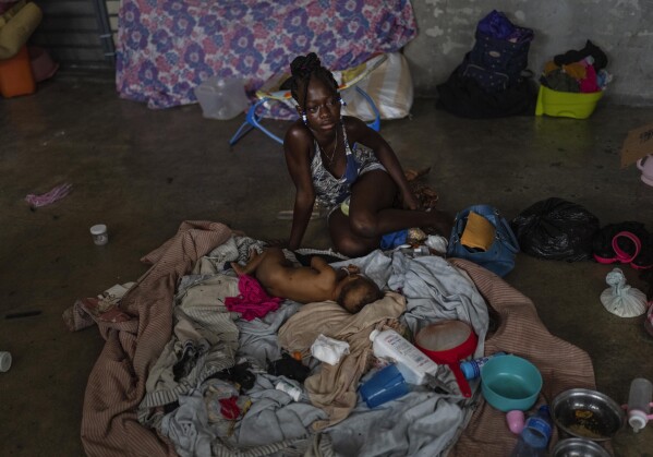 A mother sits with her baby inside a classroom at a school converted into a shelter for residents displaced by gang violence in Port-au-Prince, Haiti, Wednesday, May 8, 2024. As young Haitians are increasingly exposed to violence, the country is undergoing a wider push to dispel a long-standing taboo on seeking therapy and talking about mental health. (AP Photo/Ramon Espinosa)