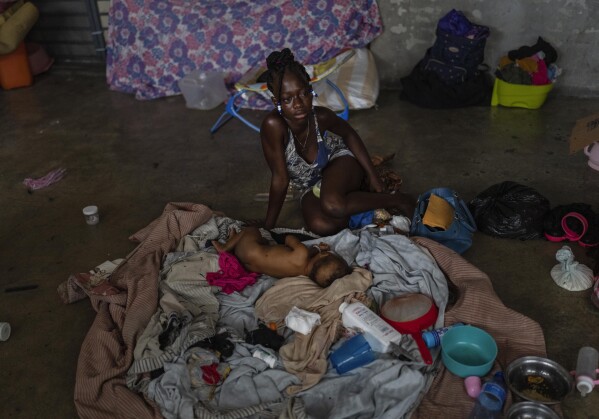 Una madre sentada con su bebé dentro de un salón de clases en una escuela convertida en refugio para residentes desplazados por la violencia de las pandillas en Puerto Príncipe, Haití, el miércoles 8 de mayo de 2024. A medida que los jóvenes haitianos están cada vez más expuestos a la violencia, el país está está realizando un esfuerzo más amplio para disipar un tabú de larga data sobre buscar terapia y hablar sobre salud mental. (Foto AP/Ramón Espinosa)