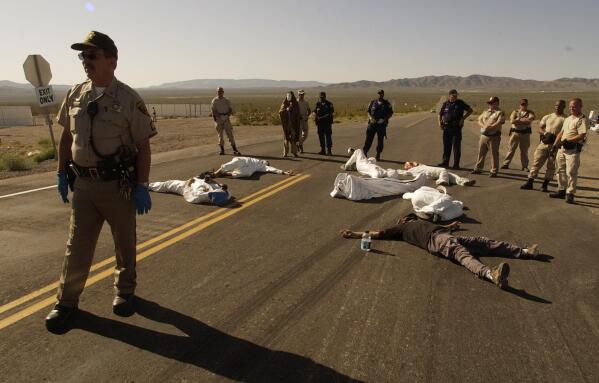 FILE - In this May 11, 2003, file photo, protesters lie on the pavement opposed to the proposed Yucca Mountain nuclear storage facility and weapons testing after crossing the line into the Nevada Test Site at Mercury, Nev., and were arrested for trespassing about 70 miles north of Las Vegas. A bipartisan group of lawmakers is renewing the push to expand a federal compensation program for radiation exposure following uranium mining and nuclear testing carried out during the Cold War. Advocates have been trying for years to bring awareness to the lingering effects of nuclear fallout surrounding the Trinity Site in southern New Mexico and on the Navajo Nation, where more than 30 million tons of ore were extracted over decades to support U.S. nuclear activities. (AP Photo/Joe Cavaretta,File)