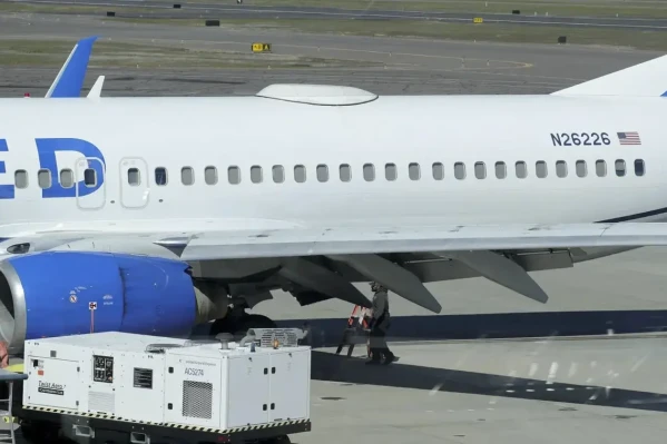 A Medford Jet Center worker walks under a United Boeing 737-824 that landed at Rogue Valley International-Medford Airport from San Francisco with a missing panel Friday, March 15, 2024, in Medford, Ore. (Andy Atkinson/Rogue Valley Times via AP)