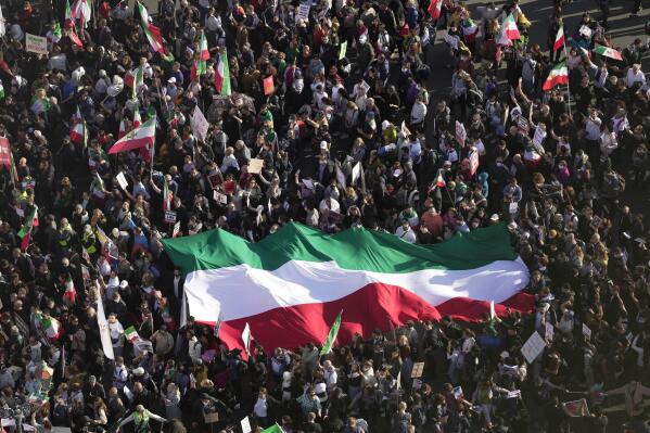 People hold Iranian flag during a protest against the Iranian regime, in Berlin, Germany, Saturday, Oct. 22, 2022, following the death of Mahsa Amini in the custody of the Islamic republic's notorious "morality police". The 22-year-old died in Iran while in police custody on Sept. 16 after her arrest three days prior for allegedly violating its strictly-enforced dress code. (AP Photo/Markus Schreiber)