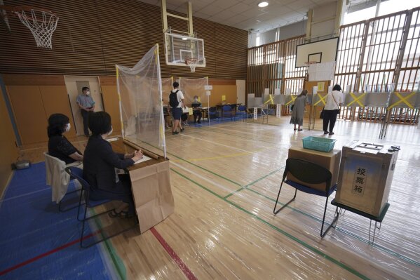 Voters prepare to cast their ballots in the Tokyo gubernatorial election as representatives of a local election administration commission observe at a polling station Sunday, July 5, 2020, in Tokyo. Gov. Yuriko Koike is poised to be reelected in Sunday’s polls, buoyed by public support for her coronavirus handling despite a recent rise in infections that has raised concerns of a resurgence of the disease. (AP Photo/Eugene Hoshiko)