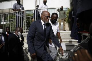 New Prime Minister Ariel Henry walks up a set of stairs escorted by his security detail after after his appointment in Port-au-Prince, Haiti, Tuesday, July 20, 2021, weeks after the assassination of President Jovenel Moise at his home. (AP Photo/Joseph Odelyn)