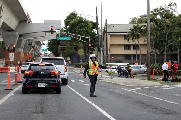 CORRECTS BYLINE TO MARCO GARCIA INSTEAD OF CALEB JONES - Police redirect traffic from the Makalapa Gate entrance to Joint Base Pearl Harbor-Hickam, Wednesday, Dec. 4, 2019, in Honolulu, following a shooting at Pearl Harbor naval shipyard. (AP Photo/Marco Garcia)