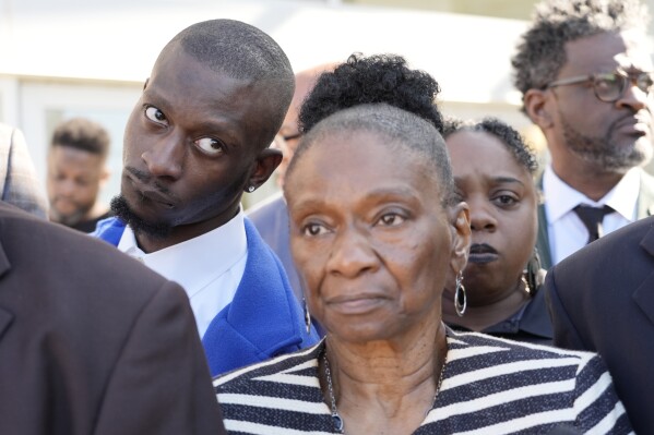 Michael Corey Jenkins, left, stands with his mother Mary Jenkins, center, outside the Thad Cochran United States Courthouse in Jackson, Miss., Tuesday, March 19, 2024, listening to reporters questions following the sentencing of the second of six former Mississippi Rankin County law enforcement officers who committed numerous acts of racially motivated, violent torture on Jenkins and his friend Eddie Terrell Parker in 2023. (AP Photo/Rogelio V. Solis)