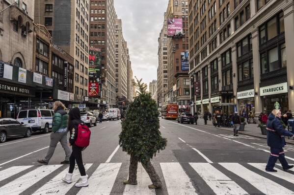 Tommy Liberto, known as Mr. Christmas Tree, crosses Seventh Avenue while visiting New York for the tenth year from Bel Air, Md., Wednesday, Dec. 4, 2024. (AP Photo/Julia Demaree Nikhinson)