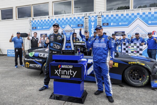 Shane van Gisbergen poses for photos with the team after his victory in the NASCAR Xfinity Series auto race at Portland International Raceway on Saturday, June 1, 2024, in Portland, Ore. (Sean Meagher/The Oregonian via AP)