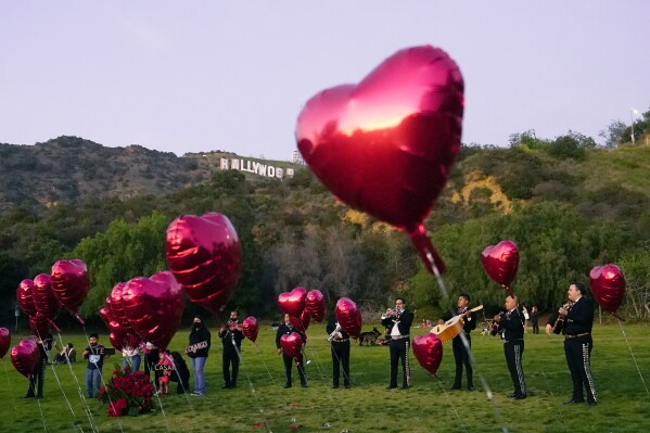 FILE - A Mexican Mariachi band surrounded by heart-shaped balloons awaits the arrival of a couple's wedding proposal ceremony at the Lake Hollywood Park in Los Angeles, on Feb. 14, 2022. This is the first Valentine's Day since the U.S. surgeon general issued a public health advisory declaring loneliness and isolation an epidemic with dire consequences. (APPhoto/Damian Dovarganes, File)