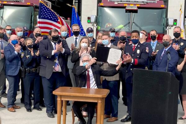 Wisconsin Gov. Tony Evers holds up a bipartisan bill he signed Tuesday, April 27, 2021, at a Madison fire station in Madison, Wis.,  that allows for police and firefighters to qualify for workers compensation if they are diagnosed with post traumatic stress disorder. (AP Photo/Scott Bauer)