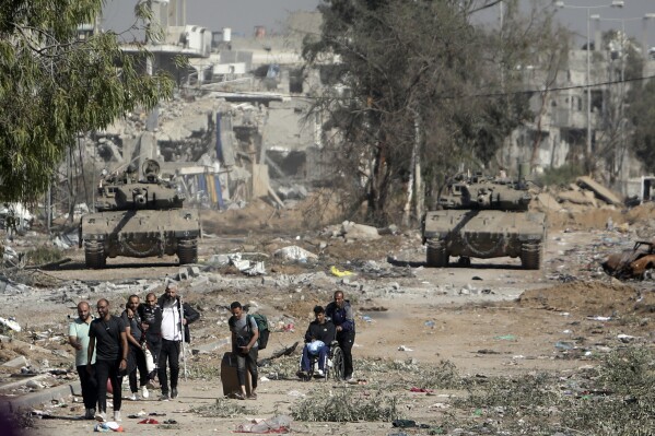 Palestinians flee to northern Gaza as Israeli tanks block the Salah al-Din road in the central Gaza Strip on Friday, Nov. 24, 2023, as the four-day cease-fire in the Israel-Hamas war begins as part of an agreement that Qatar helped broker. (AP Photo/Mohammed Dahman)