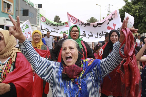 Tunisians take part in a protest against the presence of sub-Saharan migrants who have found themselves stranded as the country ramps up its border patrol efforts, in Jebeniana, Tunisia, Saturday, May 18, 2024. Anti-migrant anger is mounting in olive-growing towns along the Tunisian coastline that have emerged as a launchpad for thousands of people hoping to reach Europe by boat. Banner in Arabic reads "Deportation now." (AP Photo/Houssem Zouari)