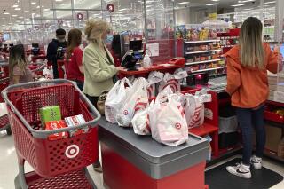 A customer wears a mask as she waits to get a receipt at a register in Target store in Vernon Hills, Ill., Sunday, May 23, 2021. Consumer spending was flat in May while incomes dropped for a second month as the impact of the government’s individual impact payments waned. (AP Photo/Nam Y. Huh)