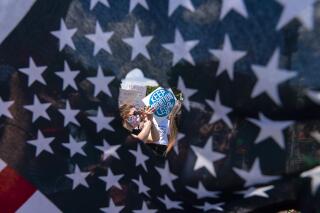 Abortion rights activists are seen through a hole in an American flag as they protest outside the Supreme Court in Washington, Saturday, June 25, 2022. The Supreme Court’s decision to overturn national protections for abortion has set off a contest between Democratic and Republican lawmakers over whose policies would do more to help vulnerable mothers and children. It's a key issue going into the midterm elections. (AP Photo/Jose Luis Magana)