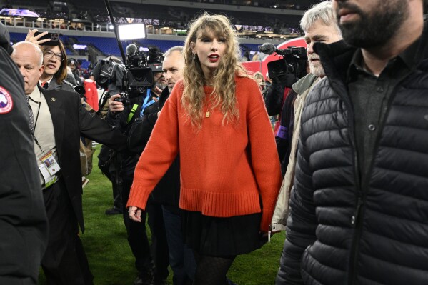 FILE - Taylor Swift walks on the field after the AFC Championship NFL football game between the Baltimore Ravens and the Kansas City Chiefs, Jan. 28, 2024, in Baltimore.  For weeks, scrutiny over Swift's travels has been mounting on social media, with people pointing out the planet-warming carbon dioxide emissions released with each flight.  (AP Photo/Nick Wass, File)