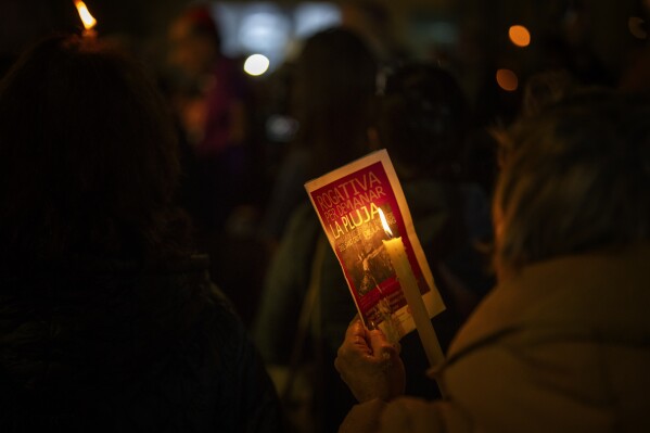 A worshipper holds a program announcing the procession of the Holy Christ of the Blood, as they march asking for rain through the streets of downtown Barcelona, Spain, Saturday, March 9, 2024. A religious procession organised by the Brotherhoods of the Archdiocese of Barcelona marched through the city downtown asking for rain coinciding with just the rainiest day of the year. Spain's northeastern region of Catalonia declared a drought emergency for the area of around 6 million people including the city of Barcelona. (AP Photo/Emilio Morenatti)