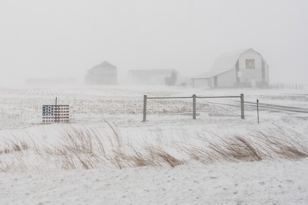 An American flag is seen fixed to a farm fence along US Highway 20 during a blizzard near Galva, Iowa, Saturday, Jan. 13, 2024. (AP Photo/Carolyn Kaster)