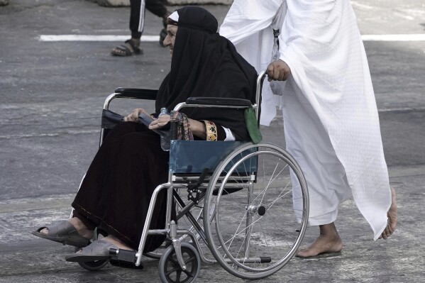 An Afghan elderly pilgrim on a wheel chair is pushed by her son, during the annual hajj pilgrimage in Mecca, Saudi Arabia, Tuesday, June 3, 2025. (AP Photo/Amr Nabil)