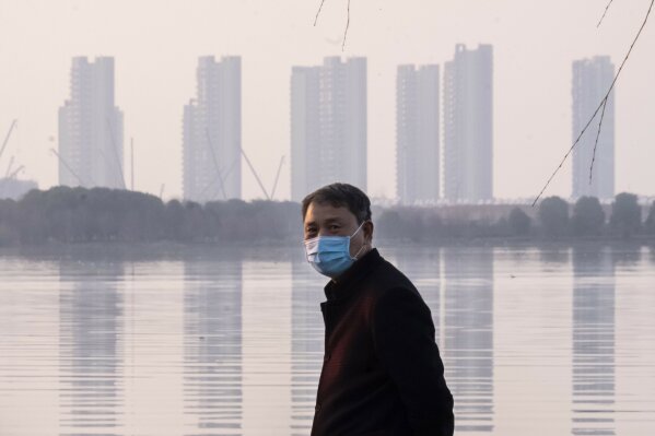 A man wears a face mask as he stands along the waterfront in Wuhan in central China's Hubei Province, Thursday, Jan. 30, 2020. China counted 170 deaths from a new virus Thursday and more countries reported infections, including some spread locally, as foreign evacuees from China's worst-hit region returned home to medical observation and even isolation. (AP Photo/Arek Rataj)