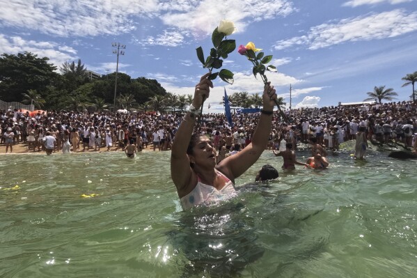 A devotee puts flowers in the waters of Arpoador Beach as offerings during an annual celebration honoring Yemanja, the African goddess of the sea, in Rio de Janeiro, Sunday, Feb. 2, 2025. (AP Photo/Bruna Prado)