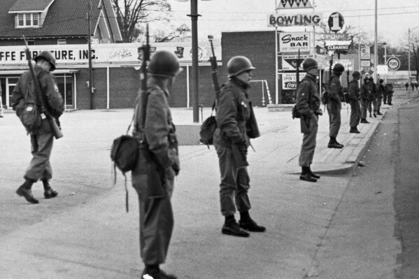 South Carolina National Guard surround a shopping center in Orangeburg, S.C., Feb. 8, 1968, after African-American students from South Carolina State College rioted the night before after being denied entrance to a bowing alley (background). (APPhoto/Dave Martin)