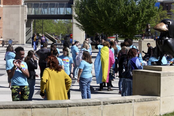 Several dozen students gather outside the Memorial Union on the University of Kansas' main campus for a campus LGBTQ+ pride photo, Friday, April 12, 2024, in Lawrence, Kan. Democratic Gov. Laura Kelly has vetoed a proposed ban on gender-affirming care for minors. (AP Photo/John Hanna)