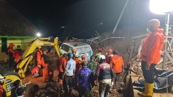 In this photo provided by the Indonesian National Disaster Mitigation Agency, rescuers work the scene of a landslide in Cihanjuang village, Indonesia, early Sunday, Jan. 10, 2021. Two landslides in the Sumedang district of West Java province triggered by heavy rain in Indonesia left multiple people dead and injured, officials said Sunday.  (Indonesian National Disaster Mitigation Agency via AP)