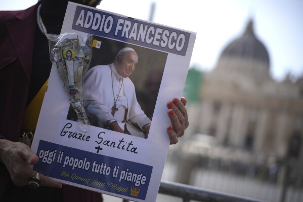 A woman holds a picture of Pope Francis reading in Italian "Farewell Francis, thank you His Holiness, today all the people cry for you" in St. Peter's Square at the Vatican after Cardinal Camerlengo Kevin Joseph Farrell announced the death of Pope Francis, Monday, April 21, 2025. (AP Photo/Andrew Medichini)