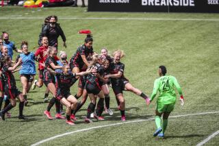 Portland Thorns teammates swarm Morgan Weaver (22) after she made the game-winning penalty kick during the NWSL Challenge Cup soccer final against NJ/NY Gotham FC at Providence Park, Saturday, May 8, 2021, in Portland, Ore. (Serena Morones/The Oregonian via AP)