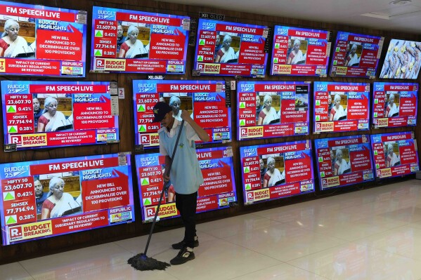 Finance Minister Nirmala Sitharaman is seen on television screens during a budget session, as a man cleans in an electronic shop in Mumbai, India, Saturday, Feb. 1, 2025.(AP Photo/Rajanish Kakade)