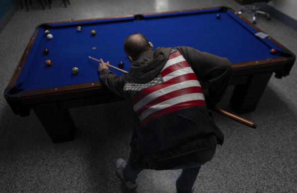 A client plays pool on a quiet afternoon at FOCUS Recovery and Wellness Community Center in Findlay, Ohio, Friday, Oct. 20, 2023. FOCUS offers free support and resources to anyone impacted by mental health, addiction, or trauma issues. The community center hosts 12-step meetings, serves meals and helps connect people with other services. (AP Photo/Carolyn Kaster)