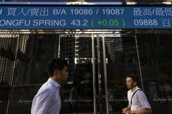 FILE - Pedestrians pass by the Hong Kong Stock Exchange electronic screen in Hong Kong, Thursday, June 29, 2023. China’s markets regulator on Friday, March 15, 2024, renewed its efforts to pep up the stock market, pledging to raise the quality of companies listed on domestic markets. (AP Photo/Louise Delmotte, File)