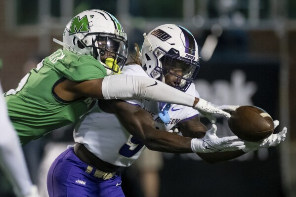 Marshall defensive back Micah Abraham, left, breaks up a pass to James Madison wide receiver Omarion Dollison (9) during the second half of an NCAA college football game in Huntington, W.Va., Thursday, Oct. 19, 2023. (Daniel Lin/Daily News-Record via AP)