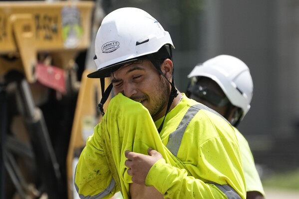 Construction worker Fernando Padilla wipes his face while working in the heat, Friday, June 30, 2023, in Nashville, Tenn. (AP Photo/George Walker IV)