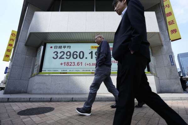 Men walk past monitors showing Japan's Nikkei 225 index at a securities firm in Tokyo, Tuesday, April 8, 2025. (AP Photo/Hiro Komae)
