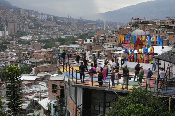 Tourists take photos in the Comuna 13 neighborhood of Medellin, Colombia, Friday, Feb. 2, 2024. Once a battleground for fighting among drug cartels, leftist guerrillas, military forces and government-linked paramilitary groups, the area is now a tourist attraction. (APPhoto/Fernando Vergara)