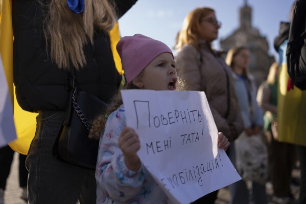 Liliia, who waits for her father to return from the frontline, holds a poster reading 