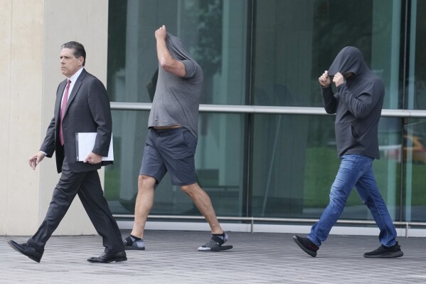 Michael Shvartsman, right, and his brother Gerald, center, leave the federal courthouse with their attorney, after posting bond, Thursday, June 29, 2023, in Miami. The two brothers and another man are charged with making $22 million through illegal insider trading before the public announcement of a Miami firm's merger with former President Donald Trump's media company. The charges do not implicate Trump or the Trump Media & Technology Group. (AP Photo/Marta Lavandier)