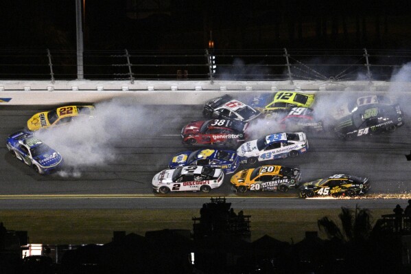 Joey Logano (22) and Daniel Suarez (99) get involved in a multi-car collision in Turn 3 during the NASCAR Daytona 500 auto race at Daytona International Speedway, Monday, Feb. 19, 2024, in Daytona Beach, Fla. (AP Photo/Phelan M. Ebenhack)