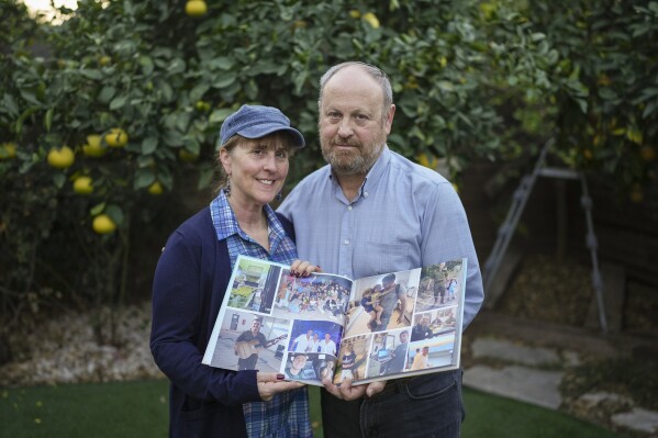 Hazel and David Brief hold a photo book made by their son Yona Brief who died 14 months after Hamas militants shot him 14 times on Oct. 7, 2024 in Kfar Aza, at their home in Modiin, Israel, Dec. 8, 2024. (AP Photo/Sam McNeil)
