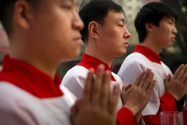 
              FILE - In this Saturday, March 31, 2018, file photo, Chinese acolytes pray during a Holy Saturday Mass on the evening before Easter at the Cathedral of the Immaculate Conception, a government-sanctioned Catholic church in Beijing. On Saturday, Sept. 22, 2018, the Vatican announced it had signed a "provisional agreement" with China on the appointment of bishops, a breakthrough on an issue that for decades fueled tensions between the Holy See and Beijing and thwarted efforts toward diplomatic relations. (AP Photo/Mark Schiefelbein, File)
            