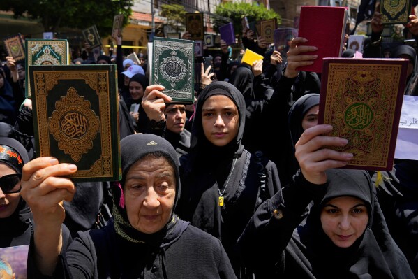 Hezbollah supporters raise the Quran during a rally after Friday prayers in the southern Beirut suburb of Dahiyeh, Lebanon, Friday, July 21, 2023. Muslim-majority nations expressed outrage Friday at the desecration of the Islamic holy book in Sweden. Following midday prayers, thousands took to the streets to show their anger, in some cases answering the call of religious and political leaders. (AP Photo/Bilal Hussein)