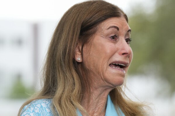 Linda Beigel Schulman, mother of geography teacher and cross country coach Scott Beigel, is overcome with emotion as she talks to journalists about visiting the scene where her son and 16 others were killed, at Marjory Stoneman Douglas High School in Parkland, Fla., Wednesday, July 5, 2023. (AP Photo/Rebecca Blackwell)